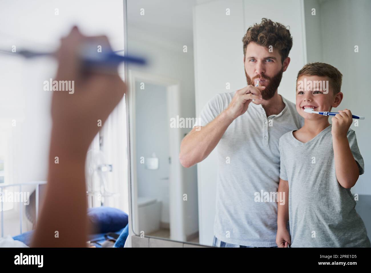 Ein Vater und sein kleiner Sohn putzen ihre Zähne zusammen im Badezimmer zu Hause. Stockfoto