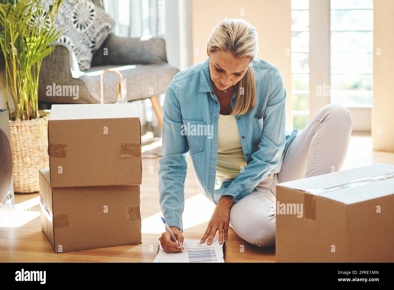 Aufzeichnungen über all ihre Habseligkeiten. Eine reife Frau, die am Umzugstag Papierkram durchläuft. Stockfoto