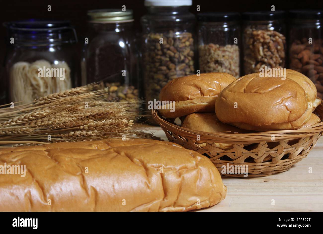 Frisch gebackenes Brot in der rustikalen Küche auf einem Holztisch mit Gläsern mit getrockneten Speisen im Hintergrund mit flachem DOF Stockfoto