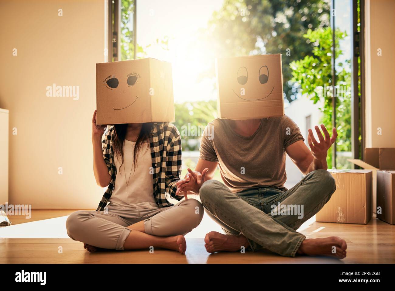 Sie sind ein Paar, das alles über Spaß und Unterhaltung weiß. Ein Paar trägt Kisten mit Smiley-Gesichtern, die auf ihren Köpfen gezeichnet sind. Stockfoto