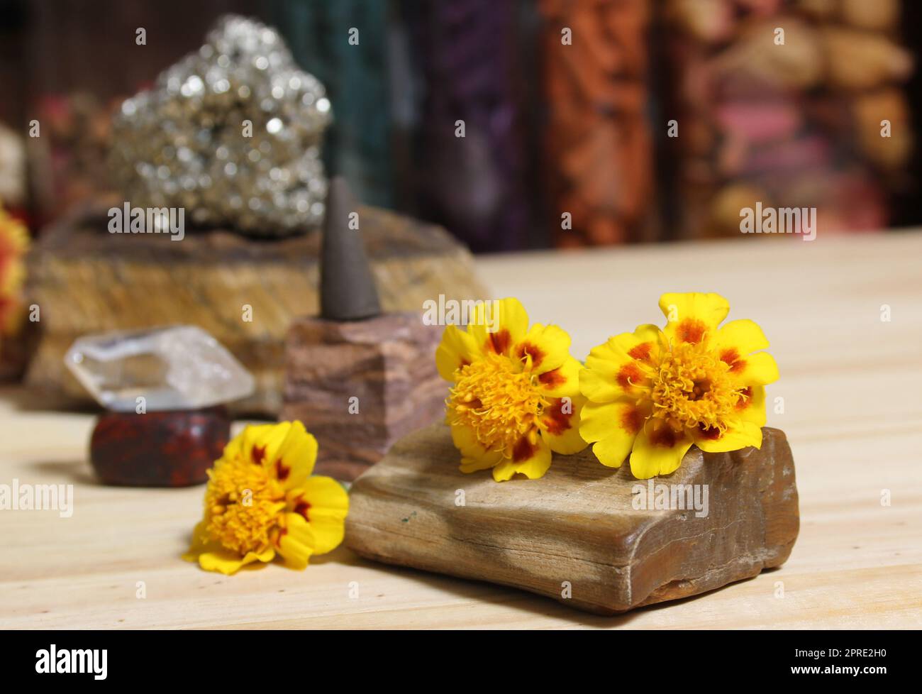 Gelbe Blumen auf versteinertem Holz mit Steinkristallen und Incense Cone Stockfoto