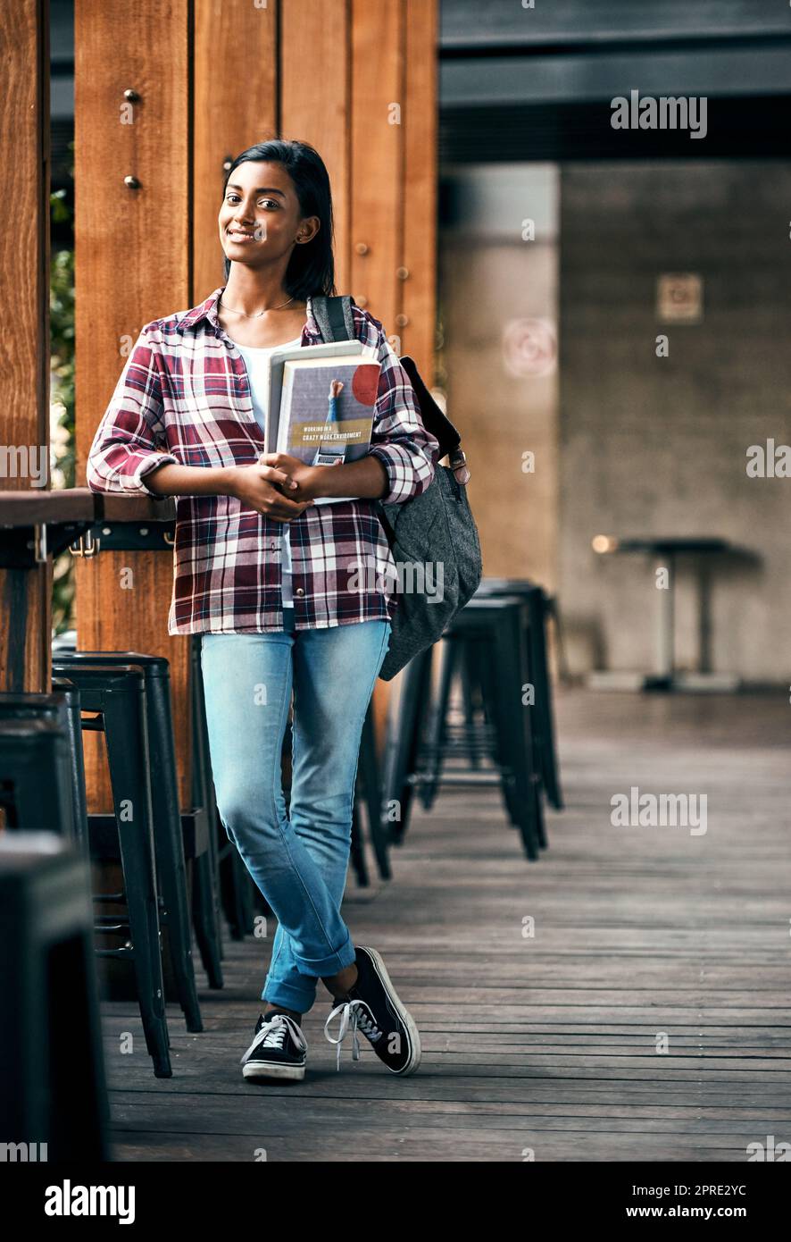 Eine junge Studentin, die Lehrbücher draußen auf dem Campus hält. Stockfoto