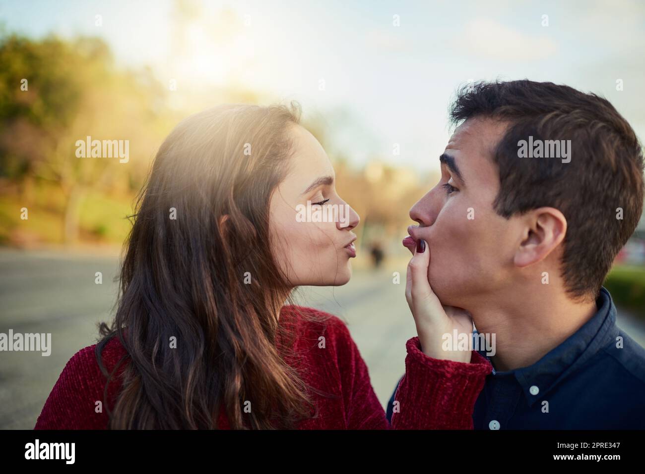 Diese Lippen sollten gerade auf meinen sein. Ein glückliches junges Paar, das einen spielerischen Moment im Freien teilt. Stockfoto