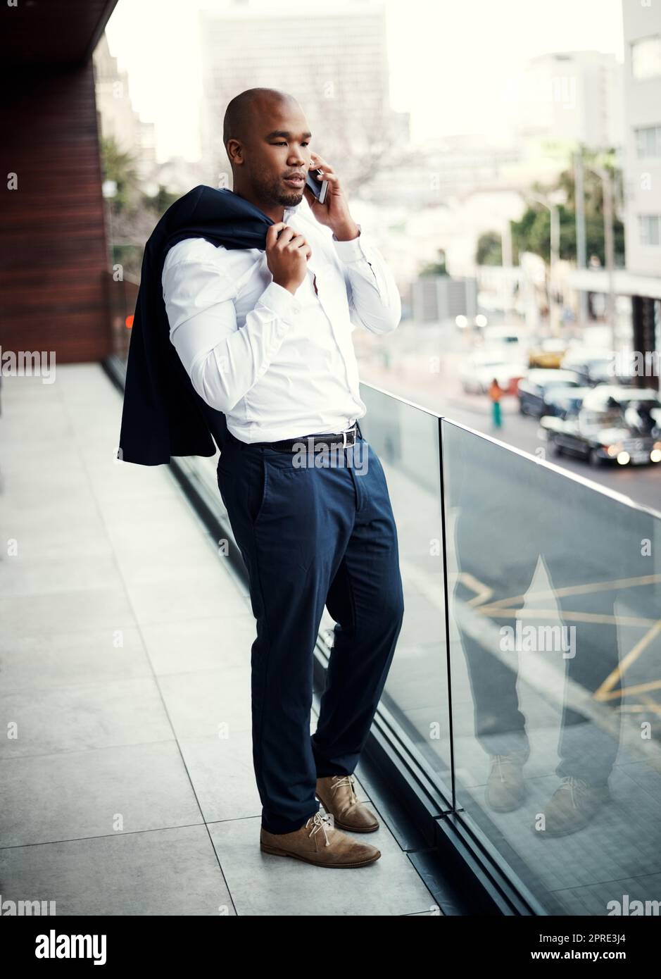 Ich bin fasziniert... Erzähl mir mehr. Ein hübscher junger Geschäftsmann, der vor seinem Büro auf einem Mobiltelefon spricht. Stockfoto