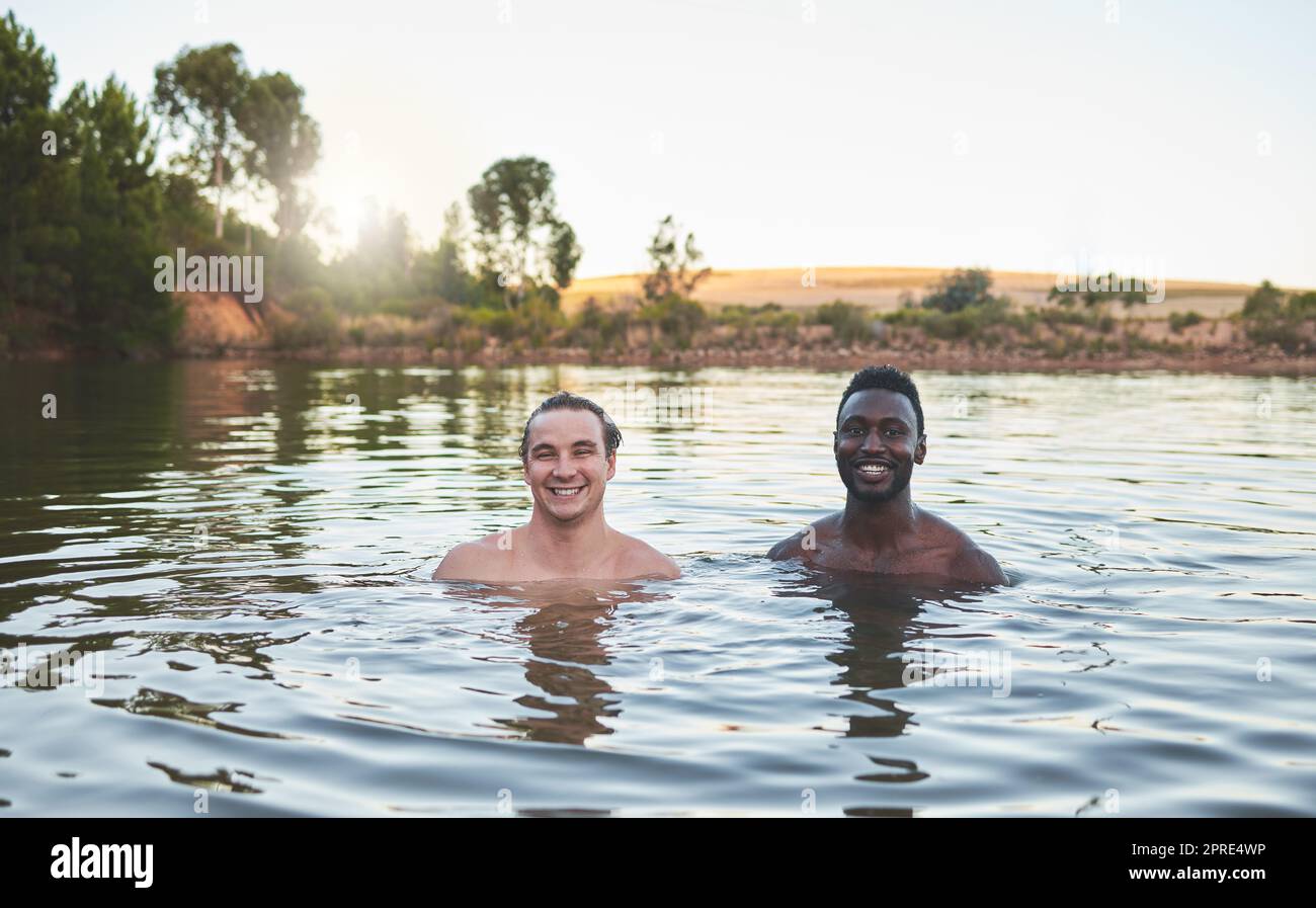 Urlaub, Freunde und Spaß beim Schwimmen in einem See und genießen den Sommer. Portrait von glücklichen und vielfältigen Kerlen, die lächeln, während sie das Wasser und die Freundschaft auf ihrer Urlaub- und Naturreise genießen Stockfoto