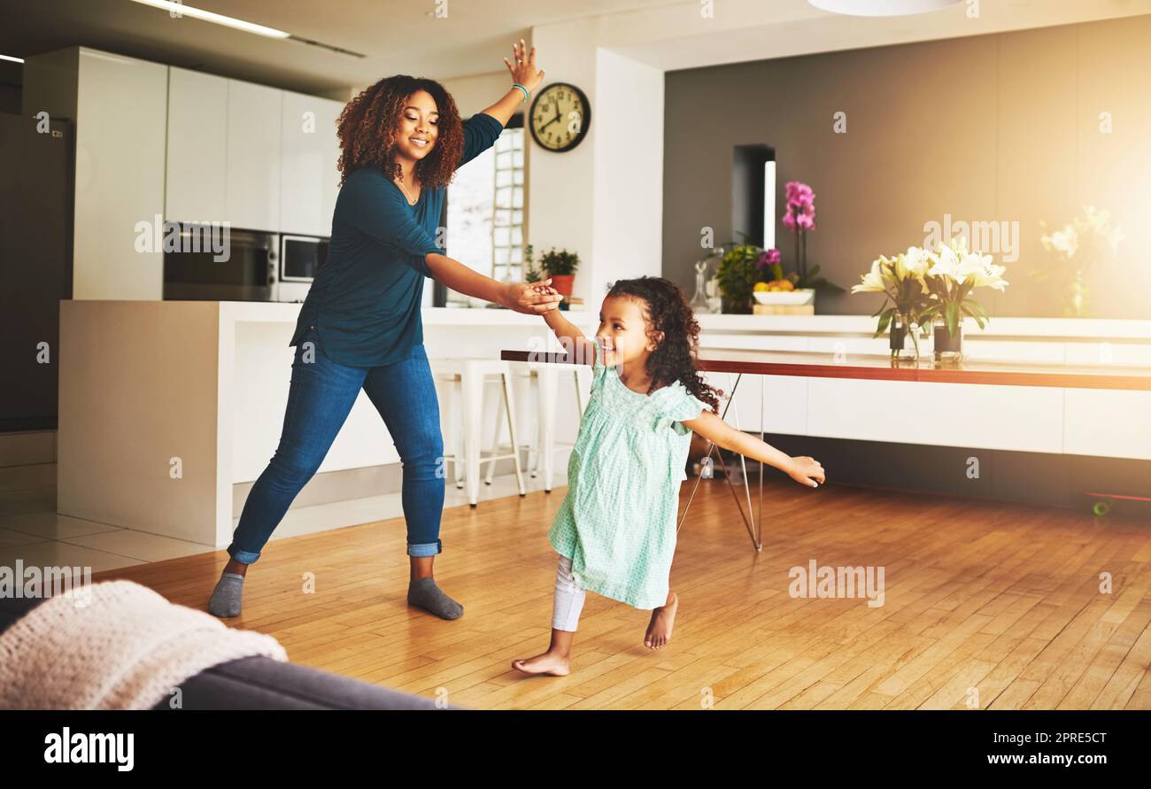 Ein kleines Mädchen und ihre Mutter tanzen zu Hause. Stockfoto