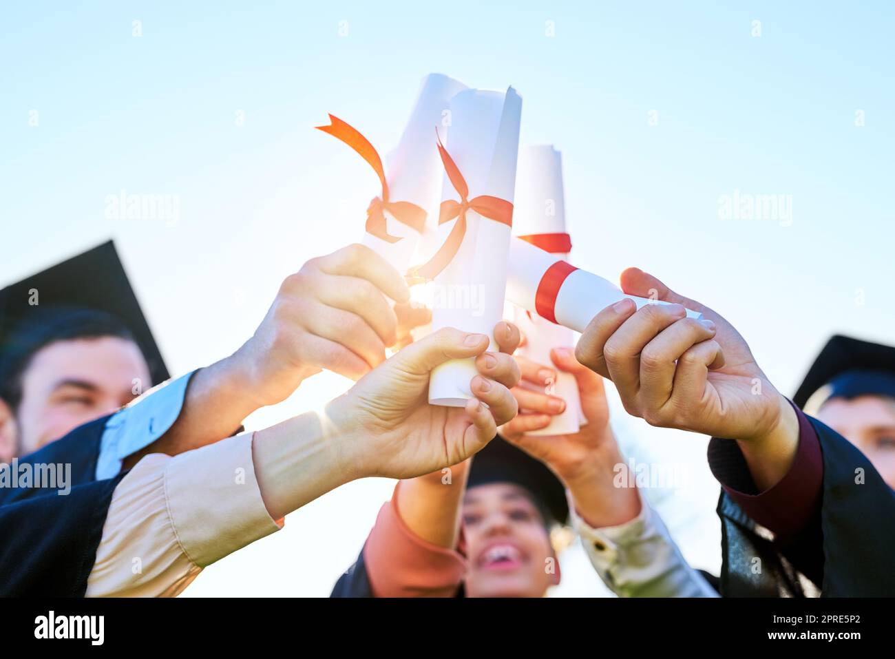 Auch verfolgen Größe mit diesen. Eine Gruppe von Studenten halten ihre Diplome zusammen am Graduierungstag. Stockfoto