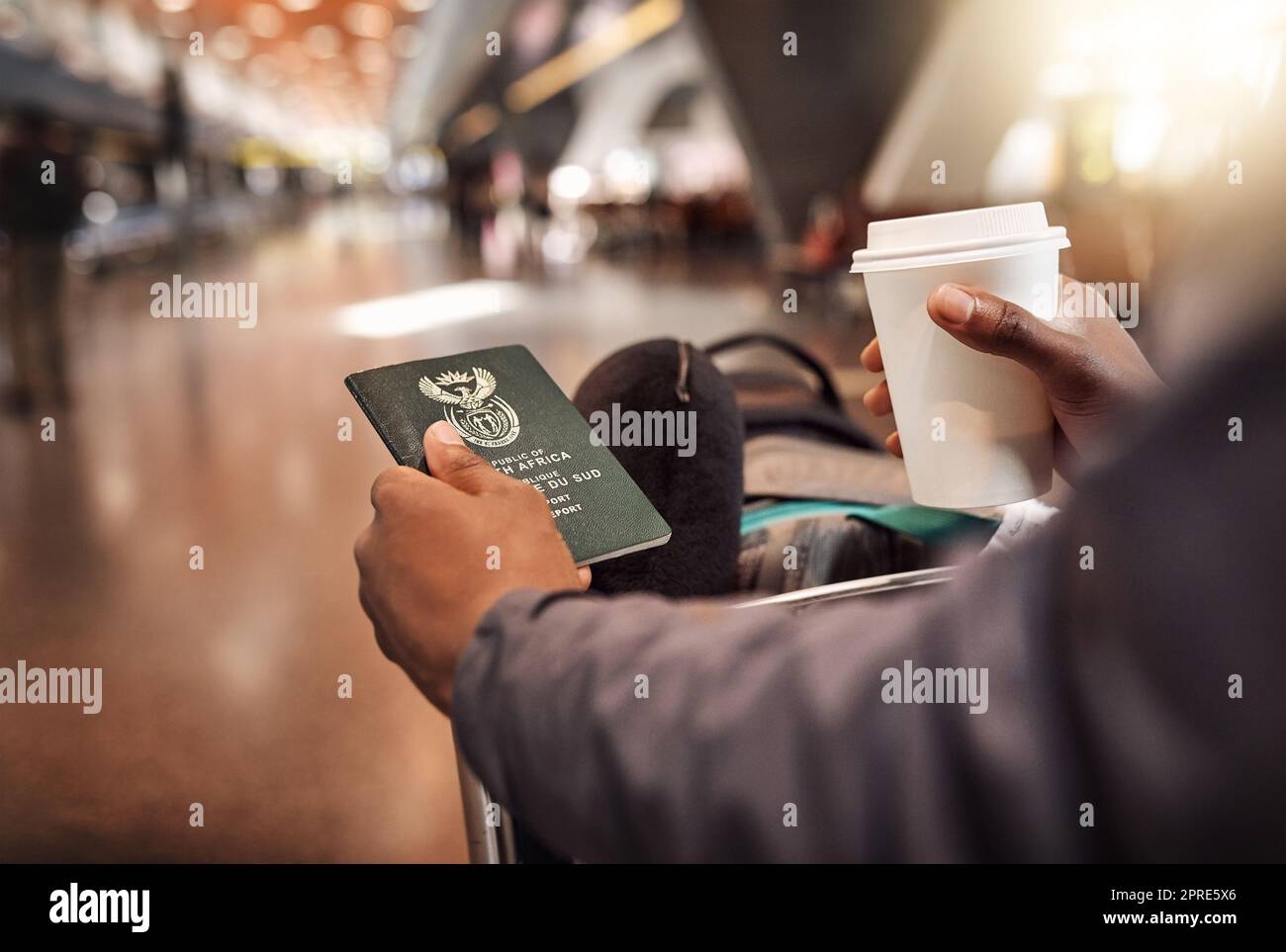 Warten auf den Boarding-Anruf. POV schoss einen nicht erkennbaren Mann, der seinen Pass und seine Bordkarte bei einem Kaffee im Flughafen hielt. Stockfoto