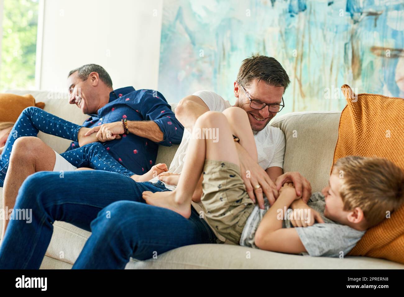 Seine kitzelige Zeit. Eine liebevolle vierköpfige Familie auf dem Sofa zu Hause. Stockfoto