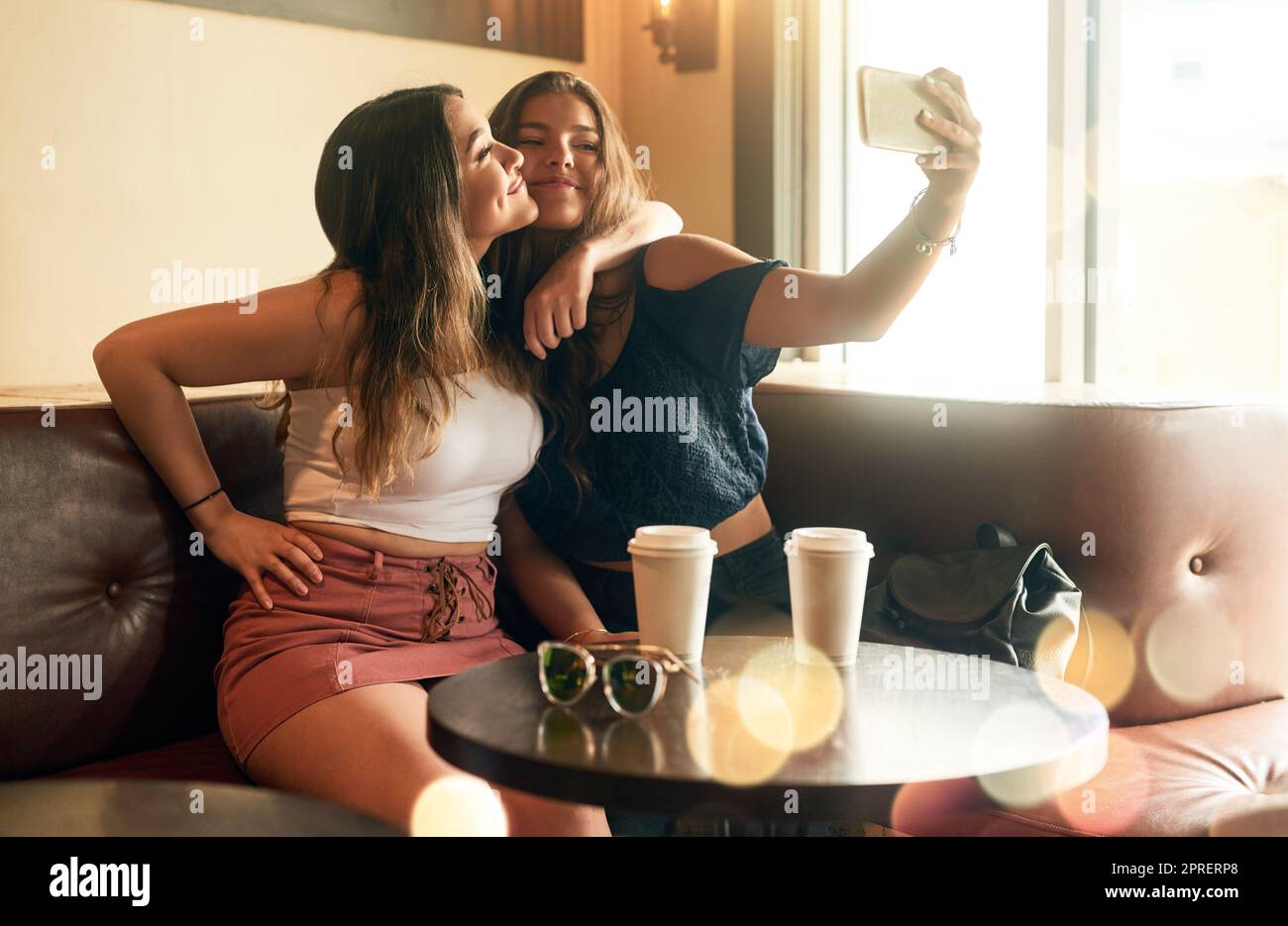 Zwei attraktive junge Frauen, die Selfies in ihrem lokalen Café machen. Stockfoto