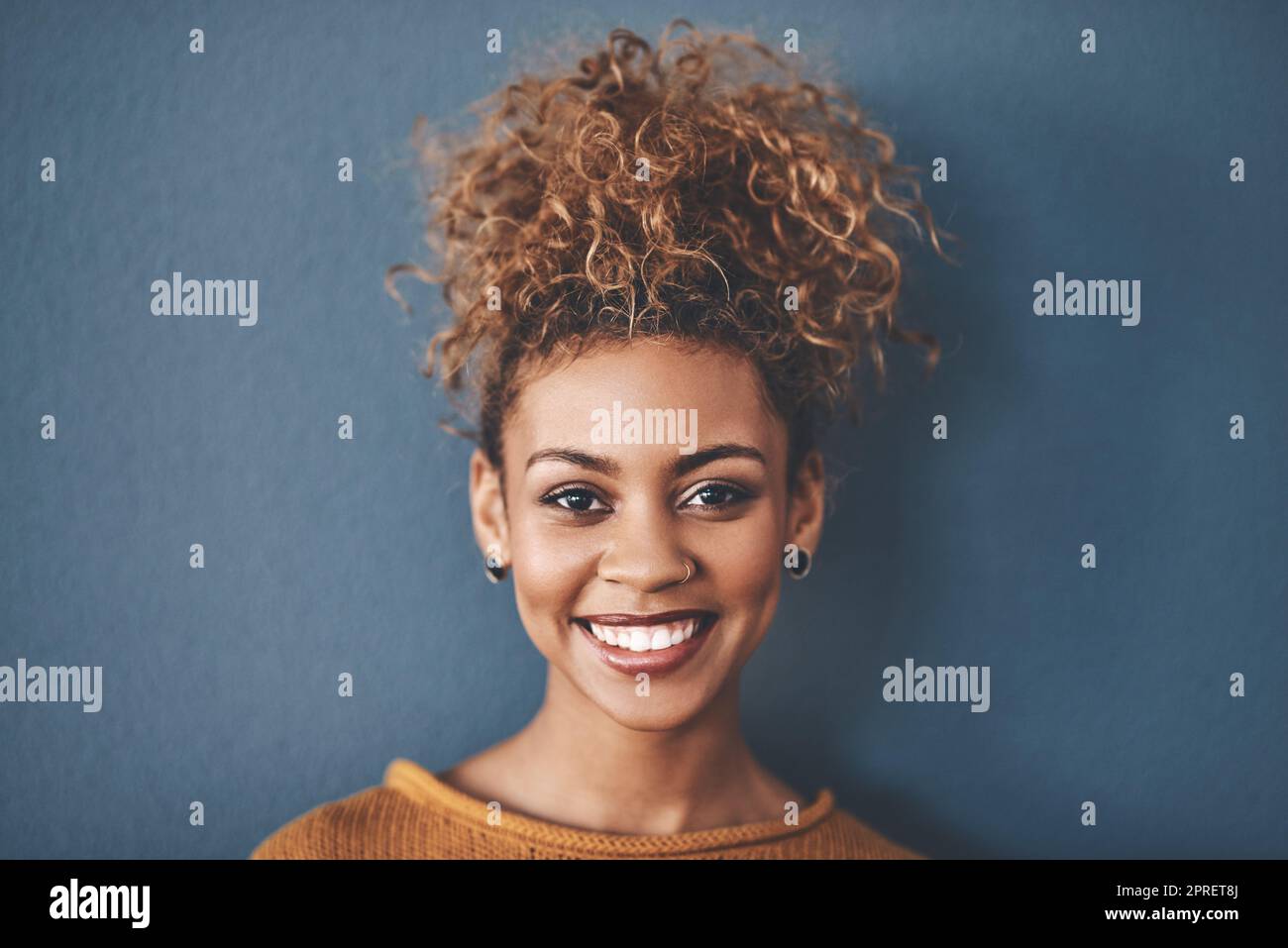 Gesicht einer glücklichen, selbstbewussten und schönen schwarzen Frau mit einer positiven Einstellung und einem strahlenden Lächeln. Porträt einer sorglosen, hübschen und attraktiven afroamerikanischen Frau, isoliert im Studiohintergrund Stockfoto