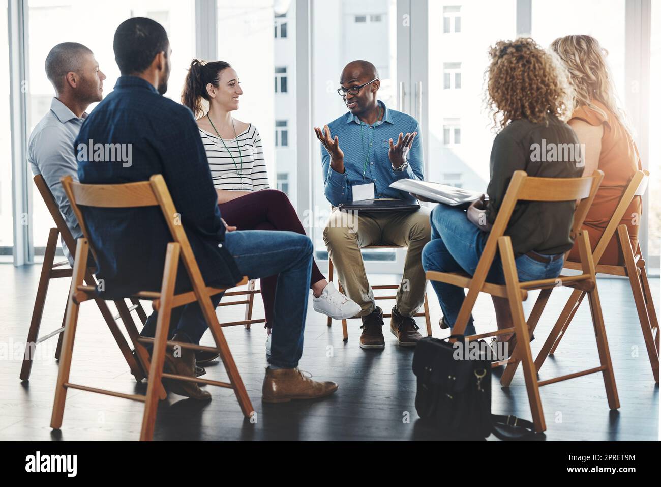 Geschäftsleute in einer informellen Besprechung, Teambuilding-Diskussion oder Projektplanungssitzung in der Gruppe. Führungskraft, Vorgesetzter oder Vorgesetzter, die mit verschiedenen Kollegen oder Mitarbeitern über Workflow-Management sprechen Stockfoto