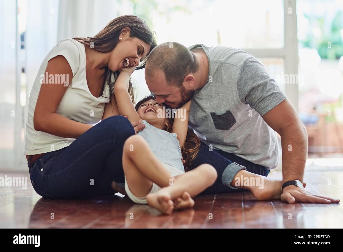 Familienzeit ist eine lustige Zeit. Eine Mutter und ein Vater verbinden sich mit ihrer entzückenden jungen Tochter zu Hause. Stockfoto