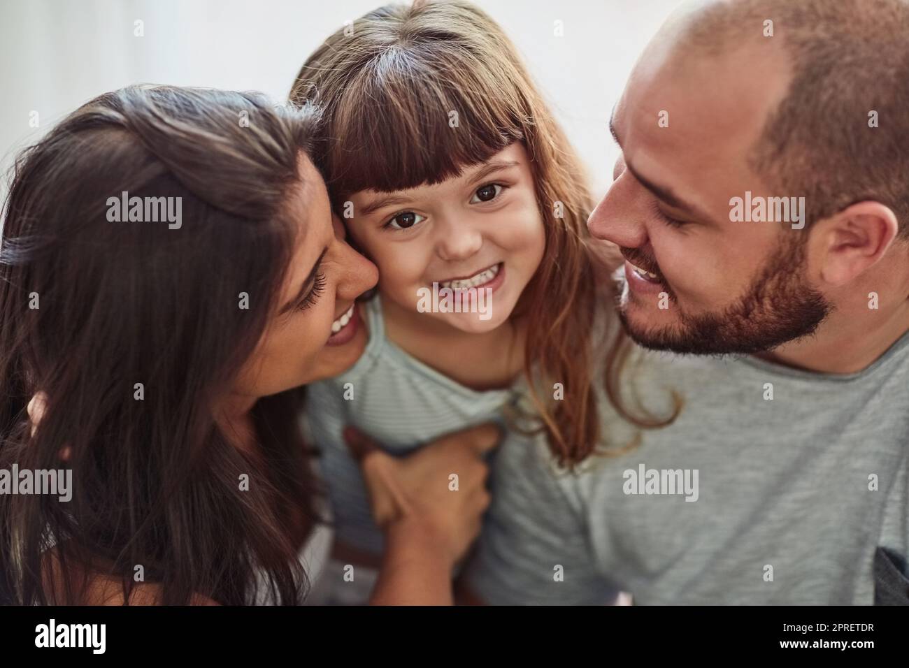 Mama und Papa lieben mich sehr. Porträt einer Mutter und eines Vaters, die sich zu Hause mit ihrer entzückenden jungen Tochter verbinden. Stockfoto