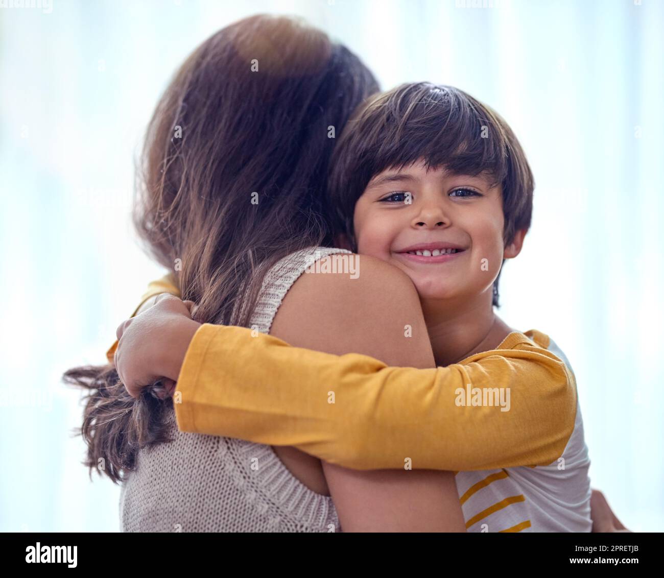Mama nennt mich ihren kleinen Mann. Ein entzückender kleiner Junge umarmt seine Mutter zu Hause liebevoll. Stockfoto