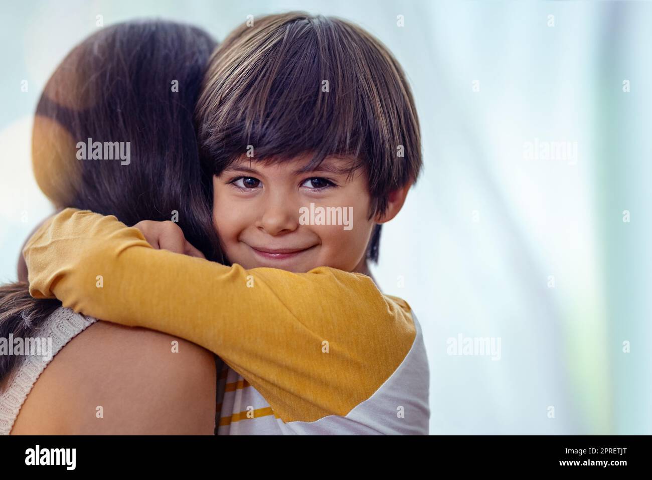 Die liebenswerteste, dauerhafteste Liebe, die es gibt. Ein entzückender kleiner Junge umarmt seine Mutter zu Hause liebevoll. Stockfoto
