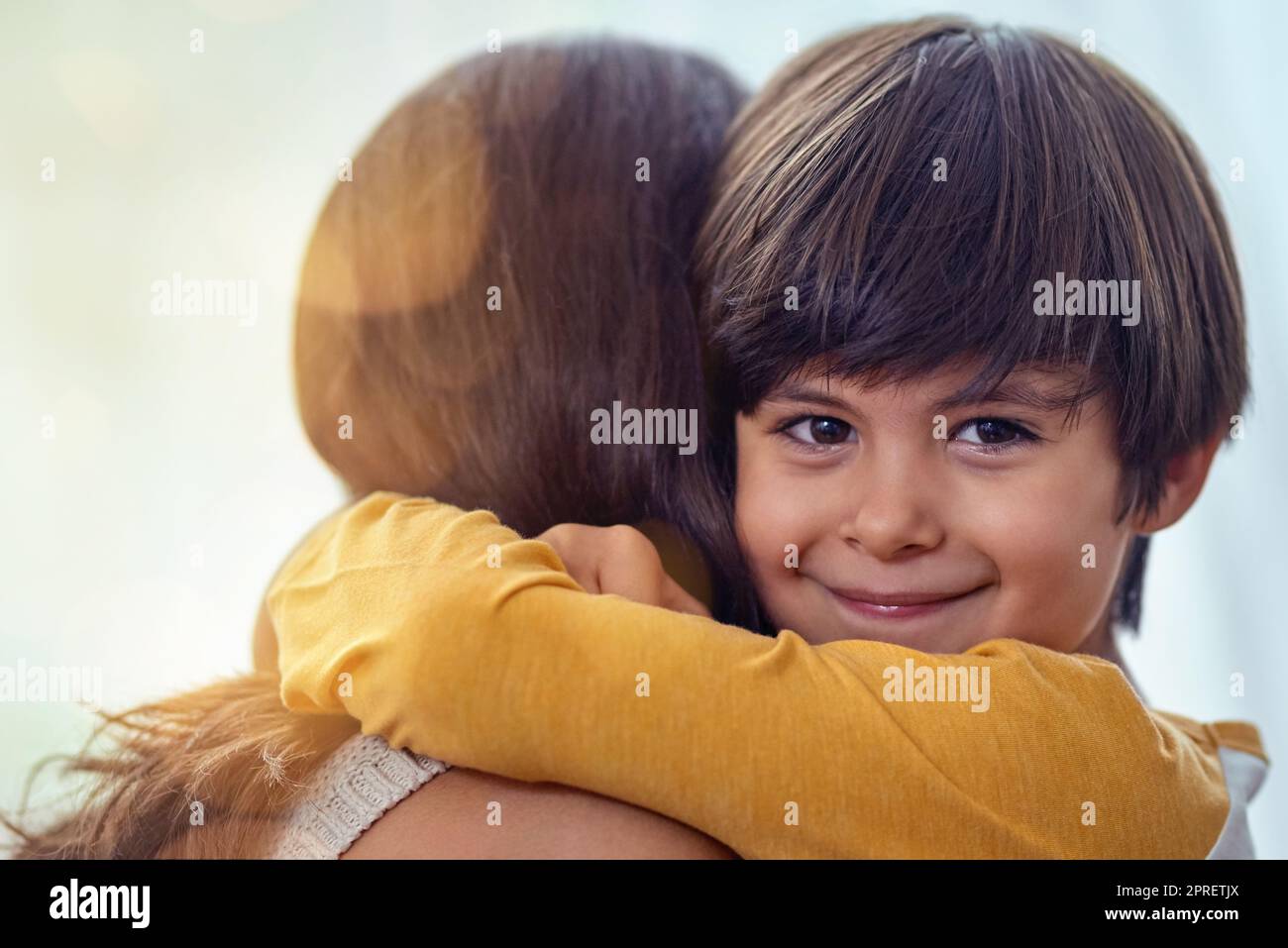 Diese Mutter-Sohn-Bindung war schon immer eine besondere. Ein entzückender kleiner Junge umarmte seine Mutter zu Hause liebevoll. Stockfoto
