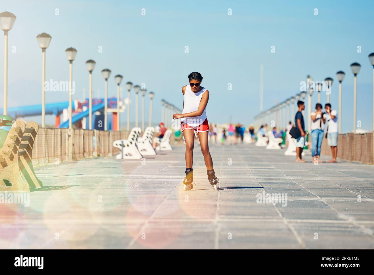 Gehen Sie hinaus und skaten Sie, bevor es zu spät ist. Eine attraktive junge Frau rollerblading auf einer Promenade. Stockfoto
