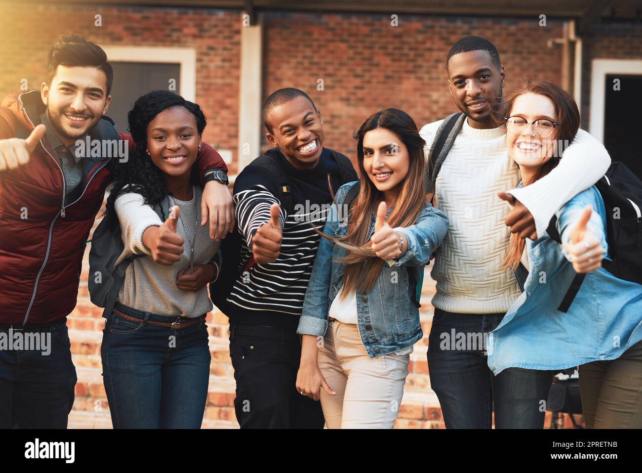 Ja zum Bildungserfolg. Porträt einer Gruppe von Studenten, die gemeinsam auf dem Campus Daumen nach oben geben. Stockfoto