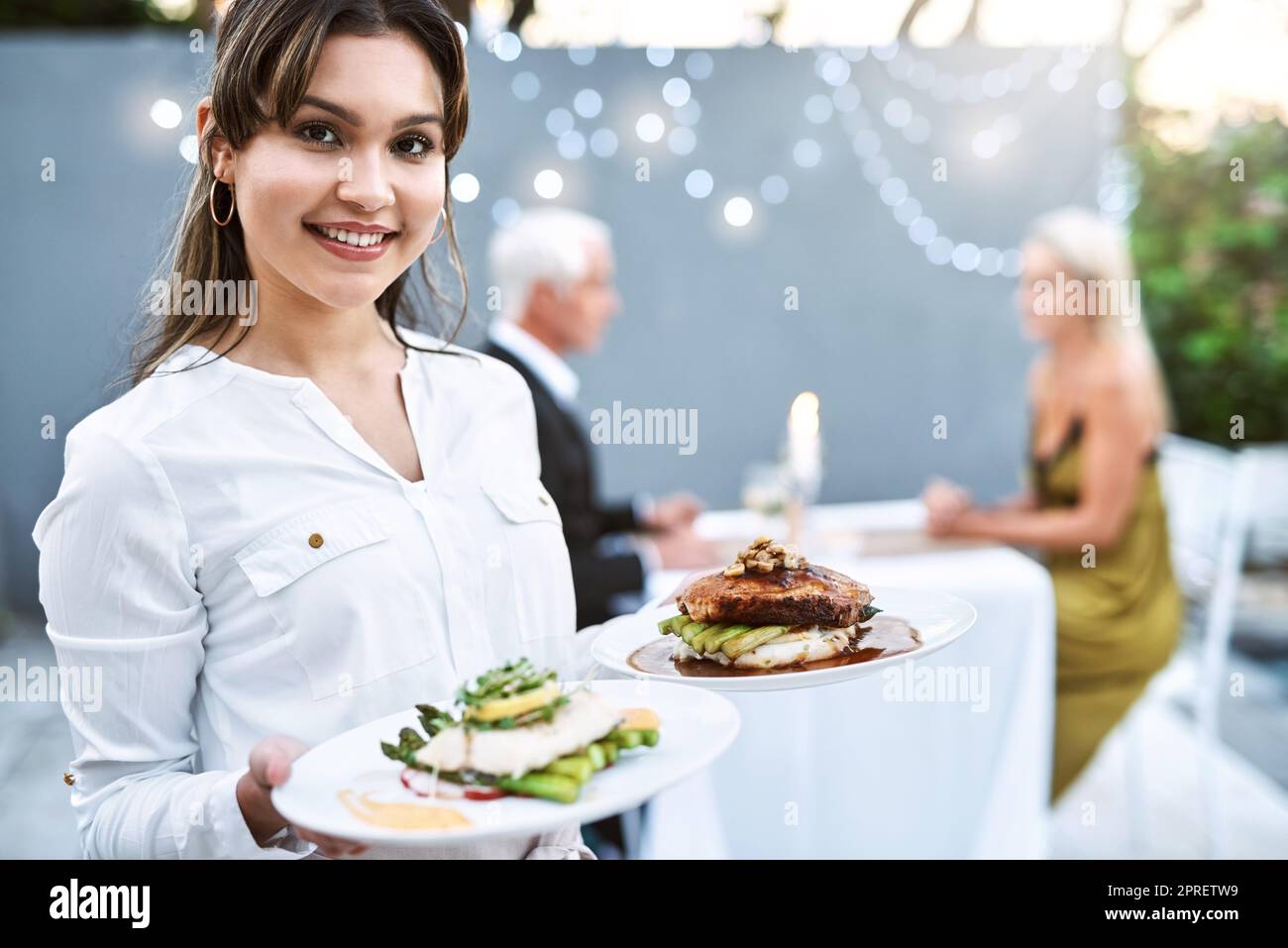 Zeit, um den Hauptgang zu dienen. Eine junge Kellnerin serviert ein reifes Paar auf einem romantischen Date. Stockfoto
