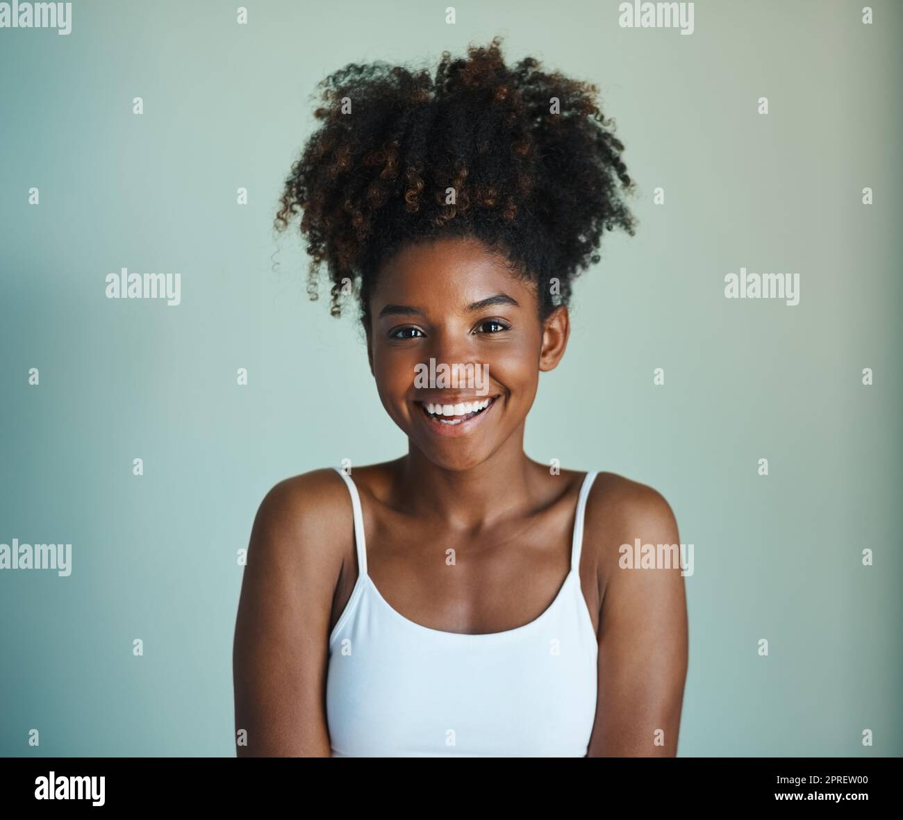 Natürliches Haar, egal. Studioaufnahme einer schönen, frisch gesichtigen jungen Frau, die vor grünem Hintergrund posiert. Stockfoto