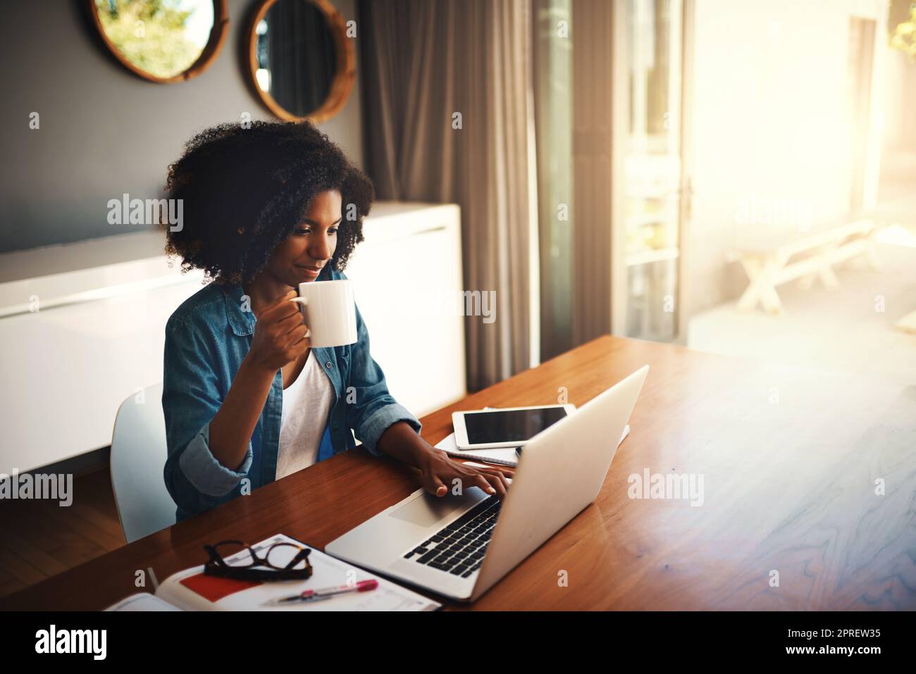 Genießen Sie die Freiheit der Freiberufung. Eine attraktive junge Frau mit einem Laptop, während Sie von zu Hause aus arbeiten. Stockfoto