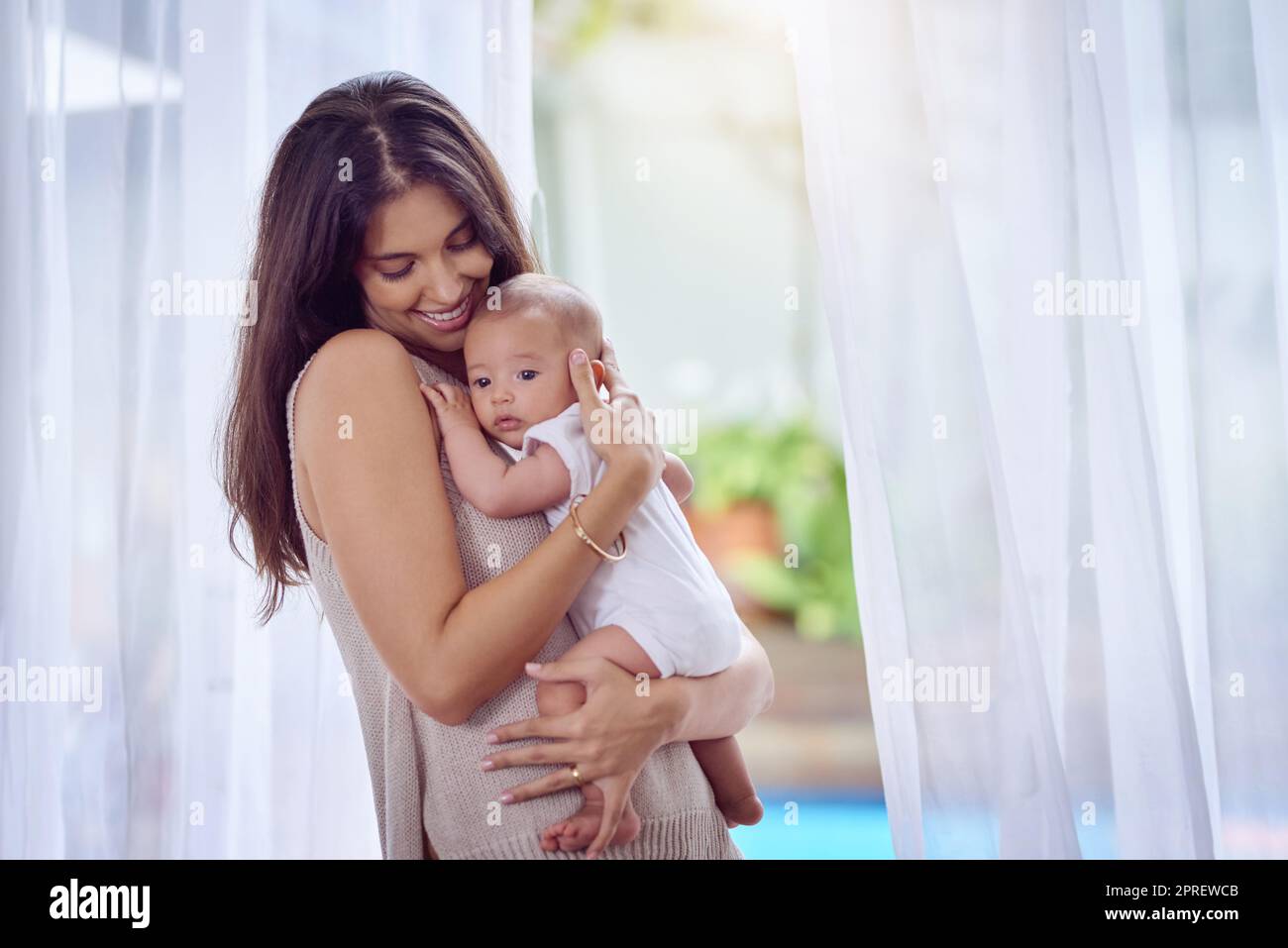 Die Arme der Mütter sind voller Liebe. Eine junge Frau, die sich zu Hause mit ihrem Jungen verklebt. Stockfoto