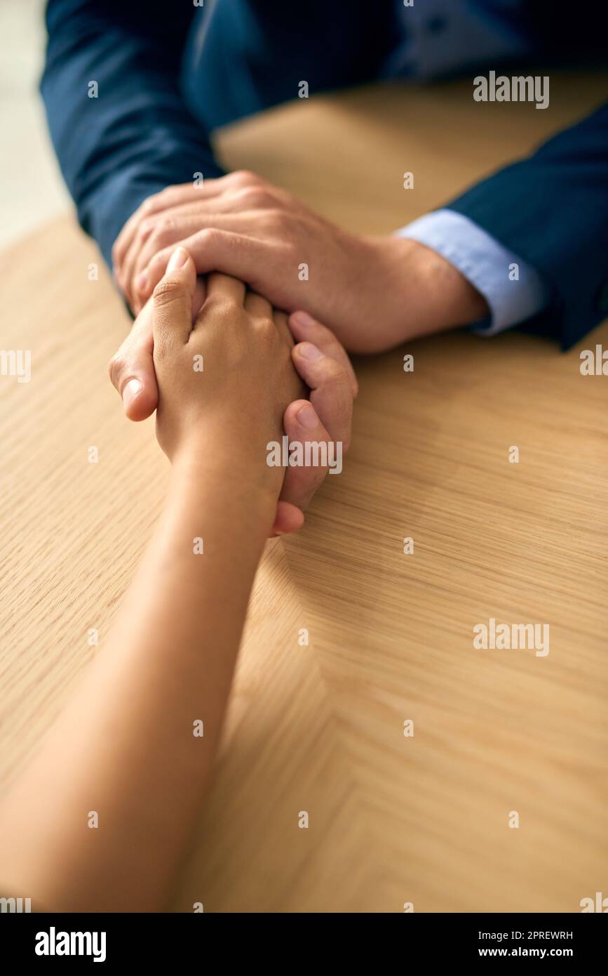 Mitgefühl mit Professionalität üben. Ein Geschäftsmann und eine Geschäftsfrau halten barmherzig die Hände an einem Tisch. Stockfoto