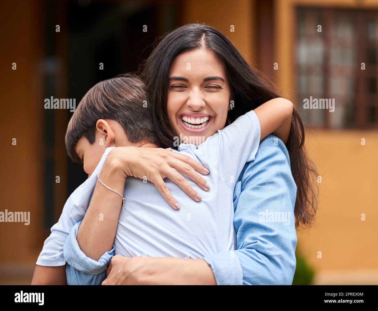 Er liebt seine Mutter so sehr. Eine junge Frau und ihr entzückender Sohn umarmen sich in ihrem Hinterhof. Stockfoto