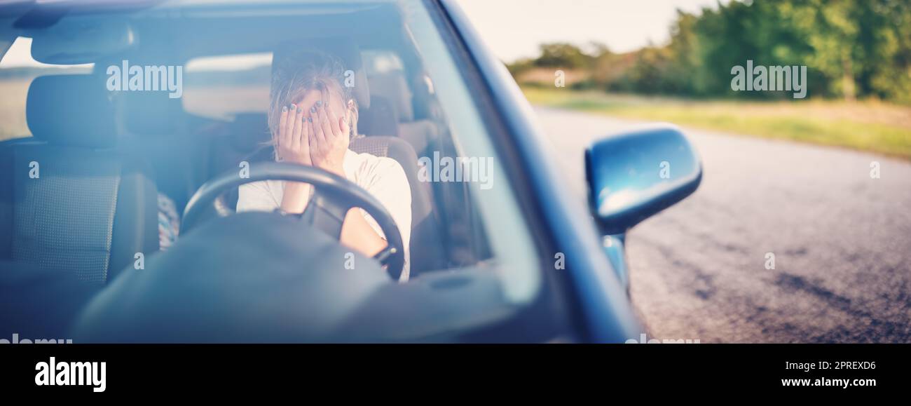 Verärgerte Frau, die im Auto sitzt und das Gesicht mit den Händen bedeckt Stockfoto