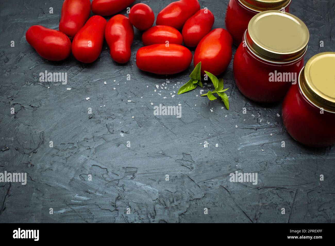 Draufsicht auf traditionelle italienische Tomatensoße in einem Glas mit frischen Tomaten und Basilikum. Speicherplatz kopieren. Stockfoto