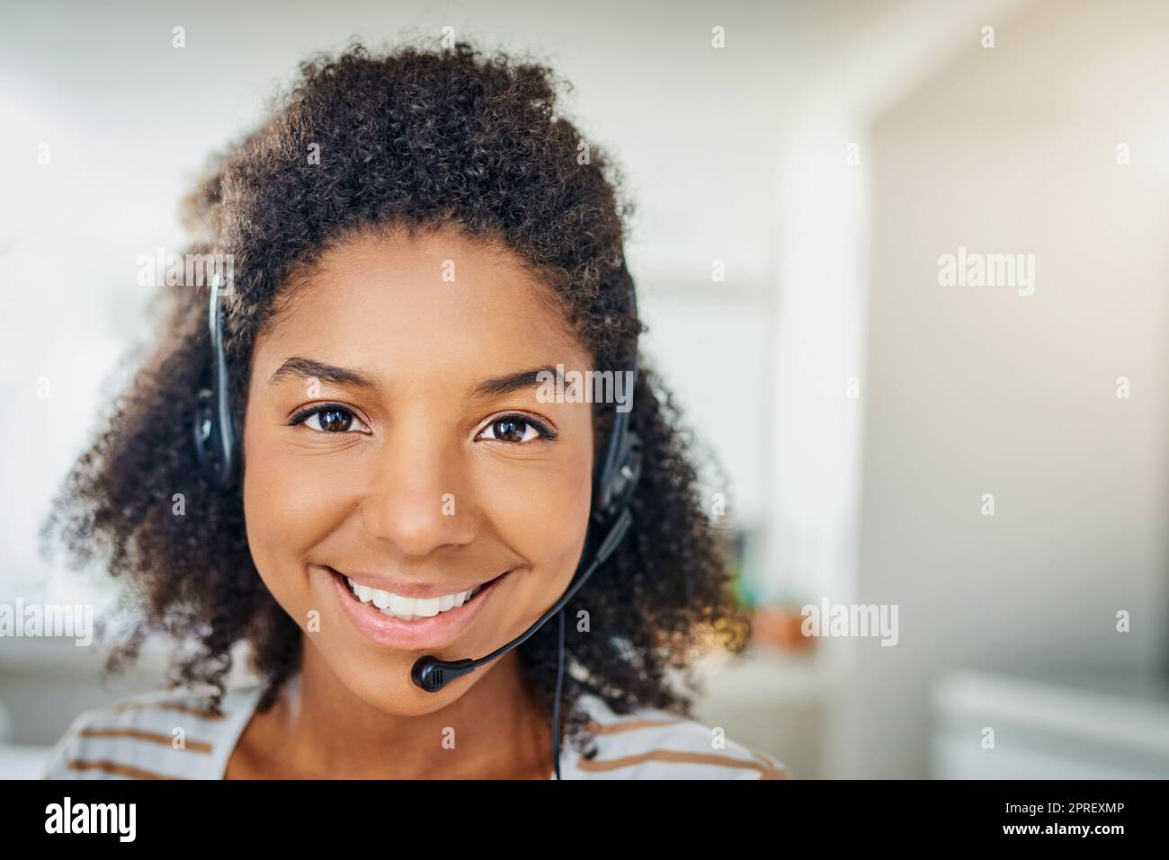 Zu Ihren Diensten. Porträt einer jungen Frau, die ein Headset trägt, während sie zu Hause arbeitet. Stockfoto