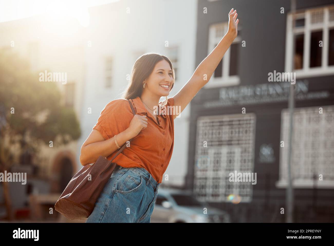 Sie winkte nach einem Taxi, wartete auf der Straße auf eine Fahrt draußen. Eine lächelnde Frau aus der Stadt möchte mit einem Taxi geschäftlich oder zum Vergnügen in die Innenstadt fahren. Gesten der Dame für den Transport mit selbstbewusstem Arm angehoben. Stockfoto