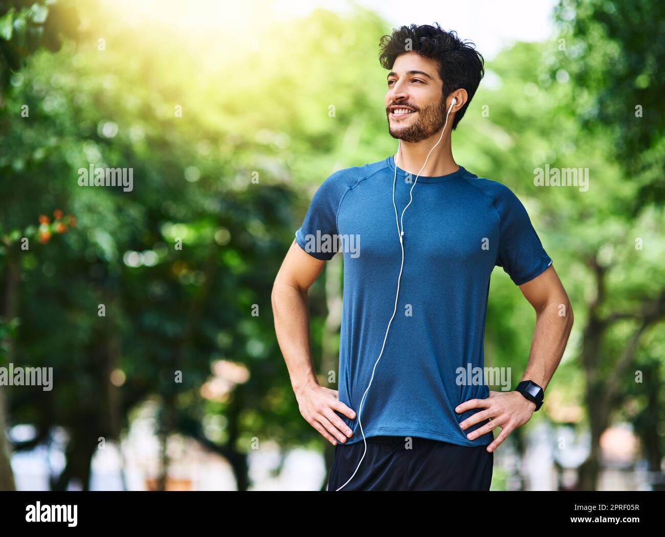 Der Einstieg in einen gesünderen Lebensstil. Ein sportlicher junger Mann, der Musik hört, während er im Freien trainiert. Stockfoto