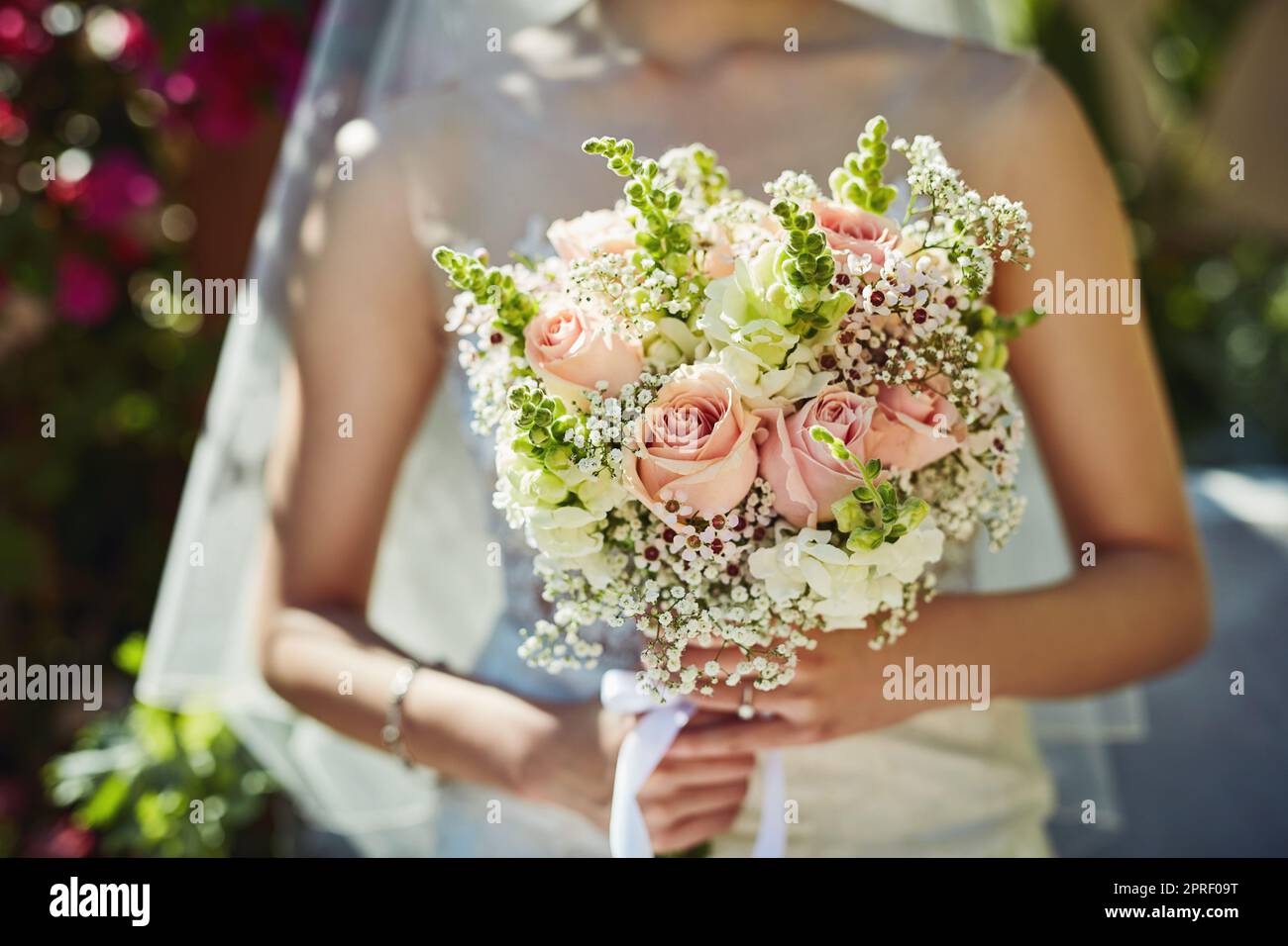 Wer das fangen wird, Frage ich mich. Eine unkenntliche Frau, die einen Blumenstrauß bei einer Hochzeit hält. Stockfoto