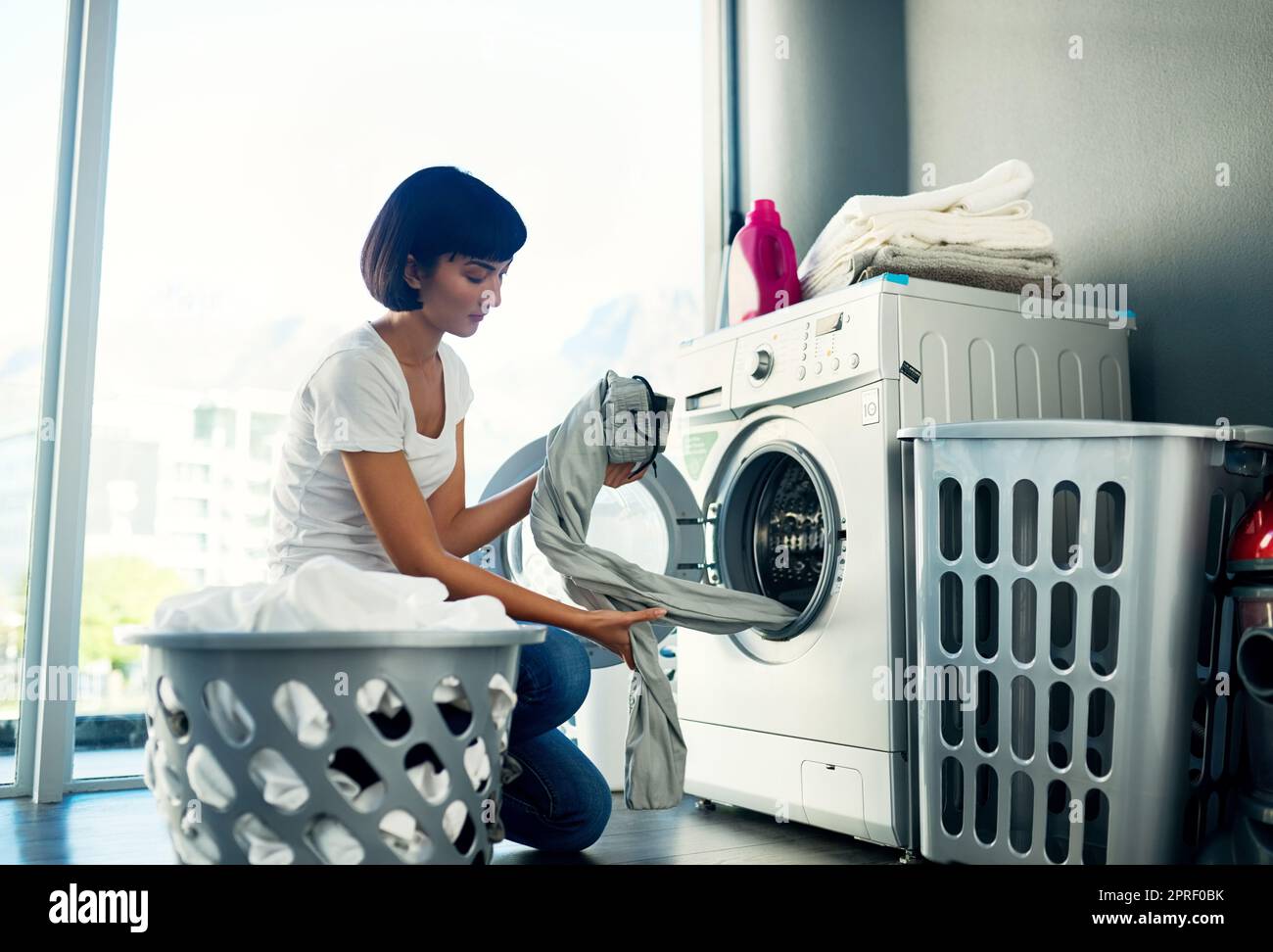 Wäsche waschen, bevor ich mich erhole. Eine junge Frau, die ihre Wäsche zu Hause macht. Stockfoto