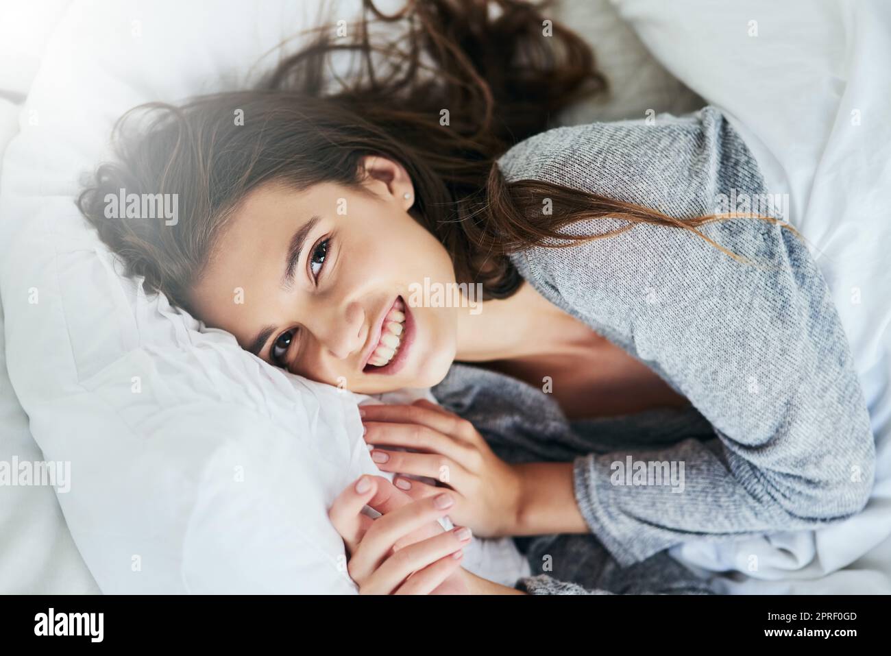 Heute schlafe ich ein. Porträt einer attraktiven jungen Frau, die tagsüber im Bett liegt und zu Hause hell lächelt. Stockfoto