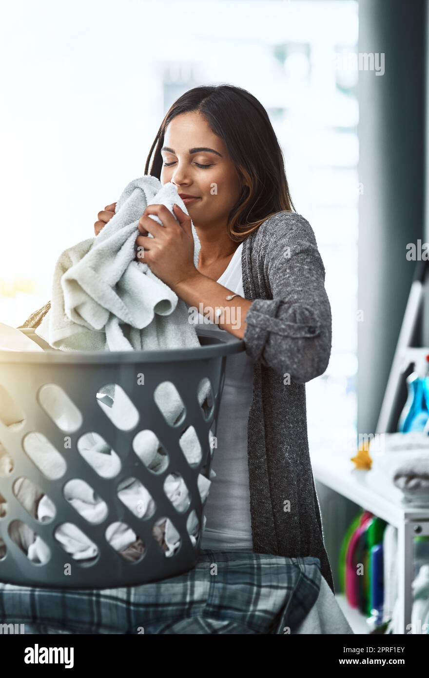 Der erfrischende Geruch von sauberer Wäsche. Eine junge attraktive Frau, die ihre Wäsche zu Hause macht. Stockfoto