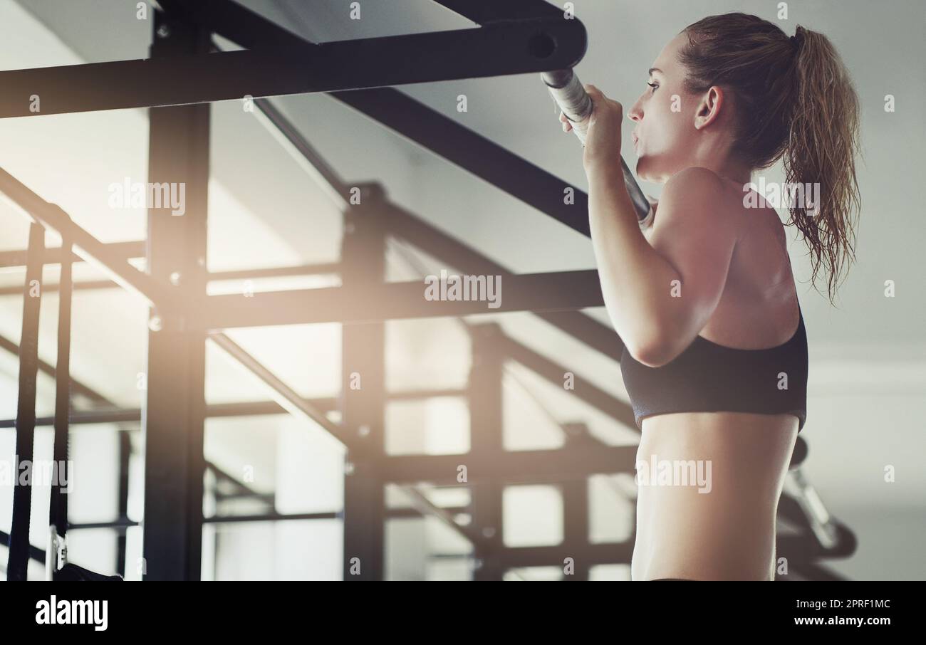 Eine attraktive junge Frau, die Pull-Ups in der Turnhalle macht. Stockfoto