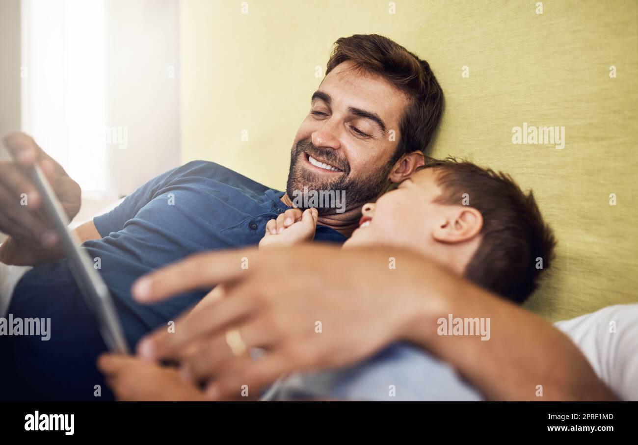 Bindungszeit im digitalen Zeitalter. Ein junger Mann, der mit seinem Sohn zu Hause ein digitales Tablet benutzt. Stockfoto