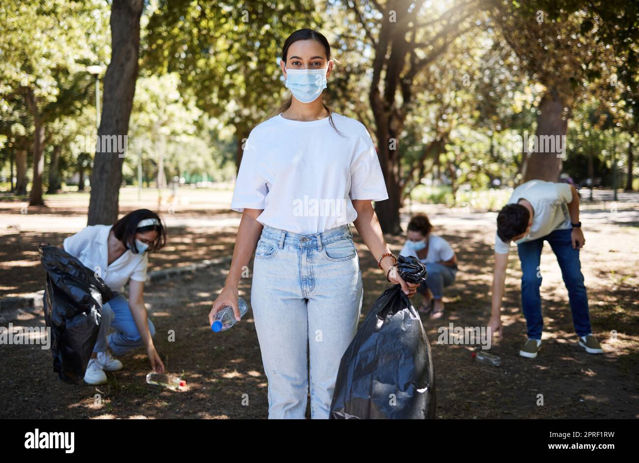 Covid, Gesichtsmaske und ehrenamtlicher Arbeiter, der den Park reinigt, gemeinnützige Arbeit leistet und dabei hilft, Müll und Plastikflaschen zu sammeln. Unterstützen Sie das Recycling-Team der Aktivisten, das gemeinsam an der Beseitigung der Umweltverschmutzung arbeitet Stockfoto