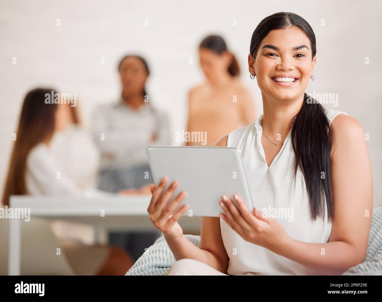 Weibliche Führungskraft, die an einem digitalen Tablet arbeitet, mit Planungszusammenarbeit und Support-Team im Hintergrundporträt. Eleganter, trendiger und modischer professioneller Stylist, der Designs auf elektronischen Geräten erstellt Stockfoto