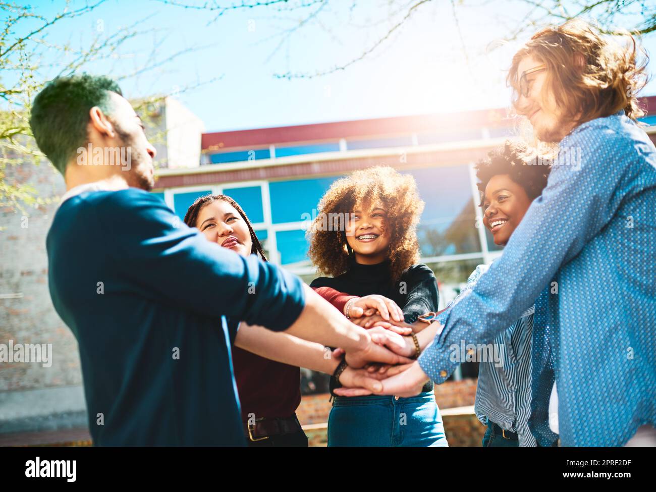 Sie kennen sie besser zusammen. Eine vielfältige Gruppe von College-Freunden, die draußen mit ihren Händen in einem Huddle stehen. Stockfoto