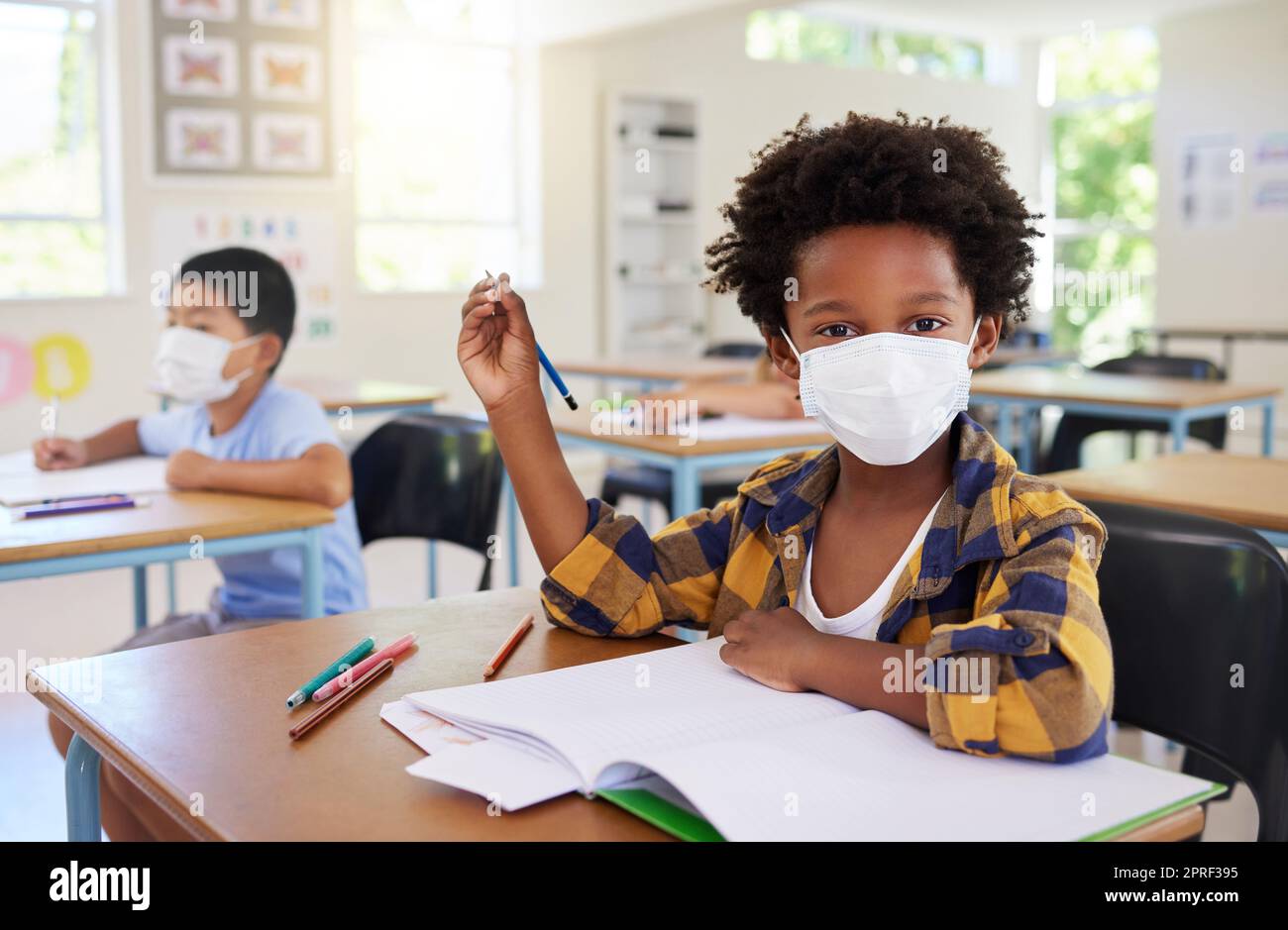 Kind oder Schüler im Unterricht während Covid, trägt eine Maske für Hygiene und Schutz vor der Coronavirus-Grippe. Porträt Kindergarten, Vorschule oder Grundschule Junge sitzt in einem Klassenzimmer und ist bereit zu lernen Stockfoto