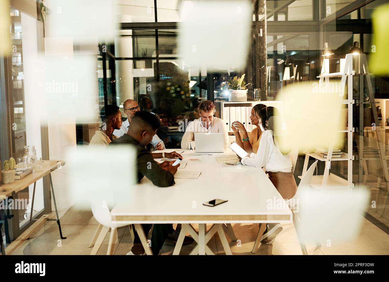 Professionelle, kreative und zwanglose Geschäftsleute treffen sich mit einem Laptop, sprechen und planen gemeinsam ein Projekt in einem Büro. Ein vielseitiges, glückliches und lächelndes Team von Mitarbeitern, das die Strategie diskutiert Stockfoto