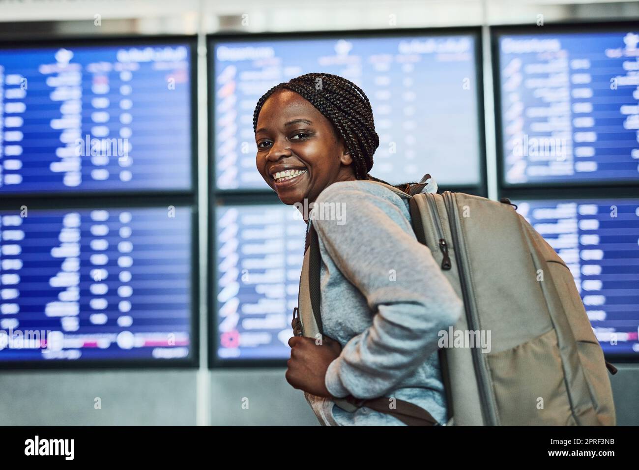Hier geht's... eine glückliche junge Frau am Flughafen. Stockfoto