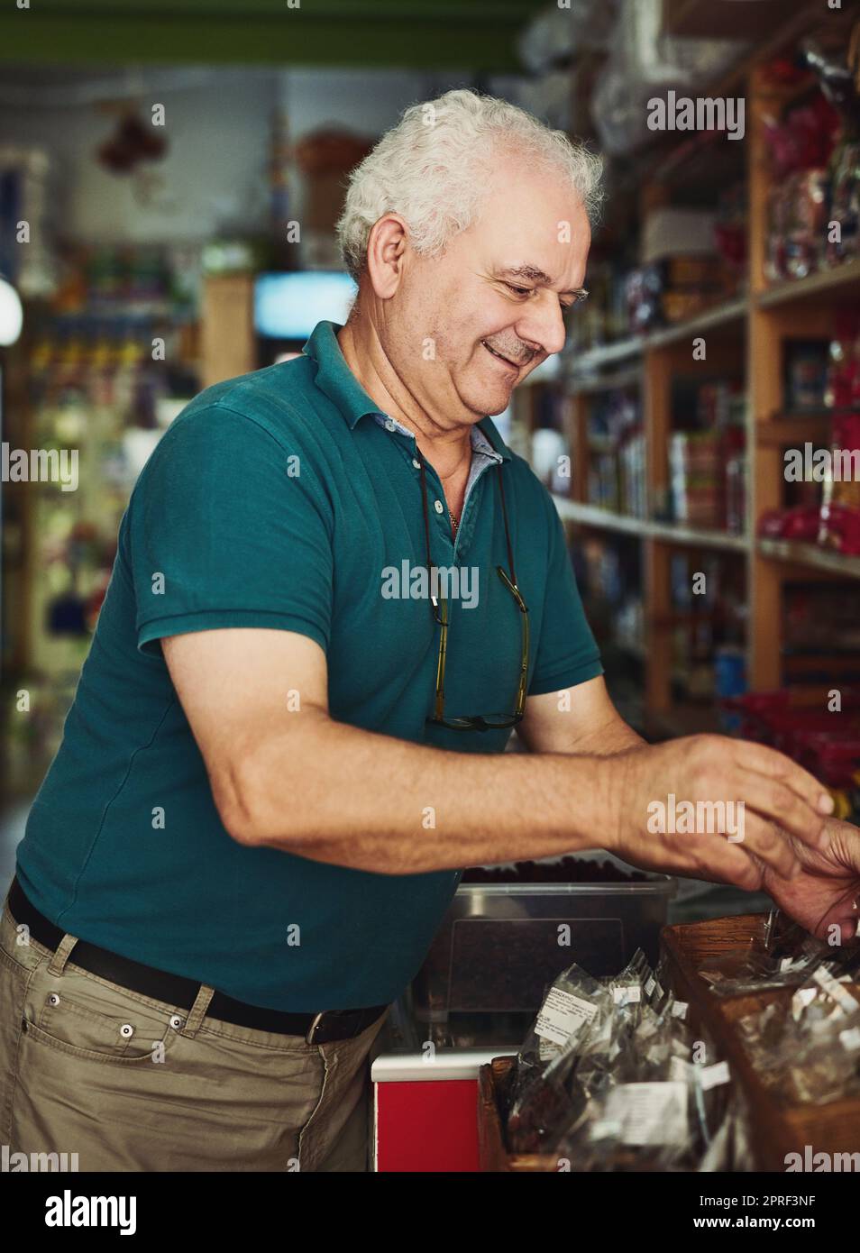 Mein Geschäft ist mein glücklicher Ort. Ein älterer Mann, der in einem Geschäft arbeitet. Stockfoto