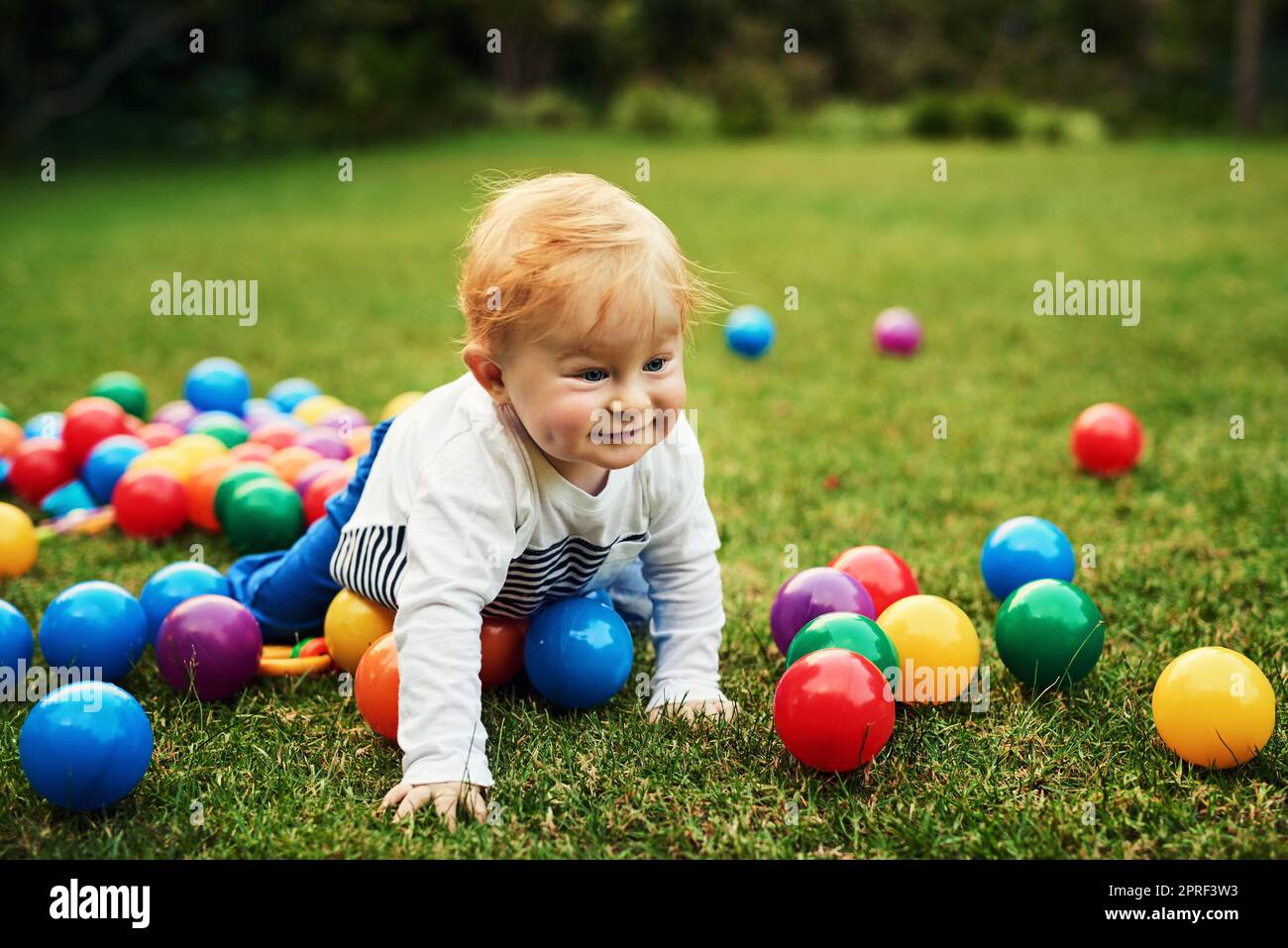 Bunte Kugeln hier komme ich. Ein entzückender kleiner Junge spielt im Hinterhof. Stockfoto