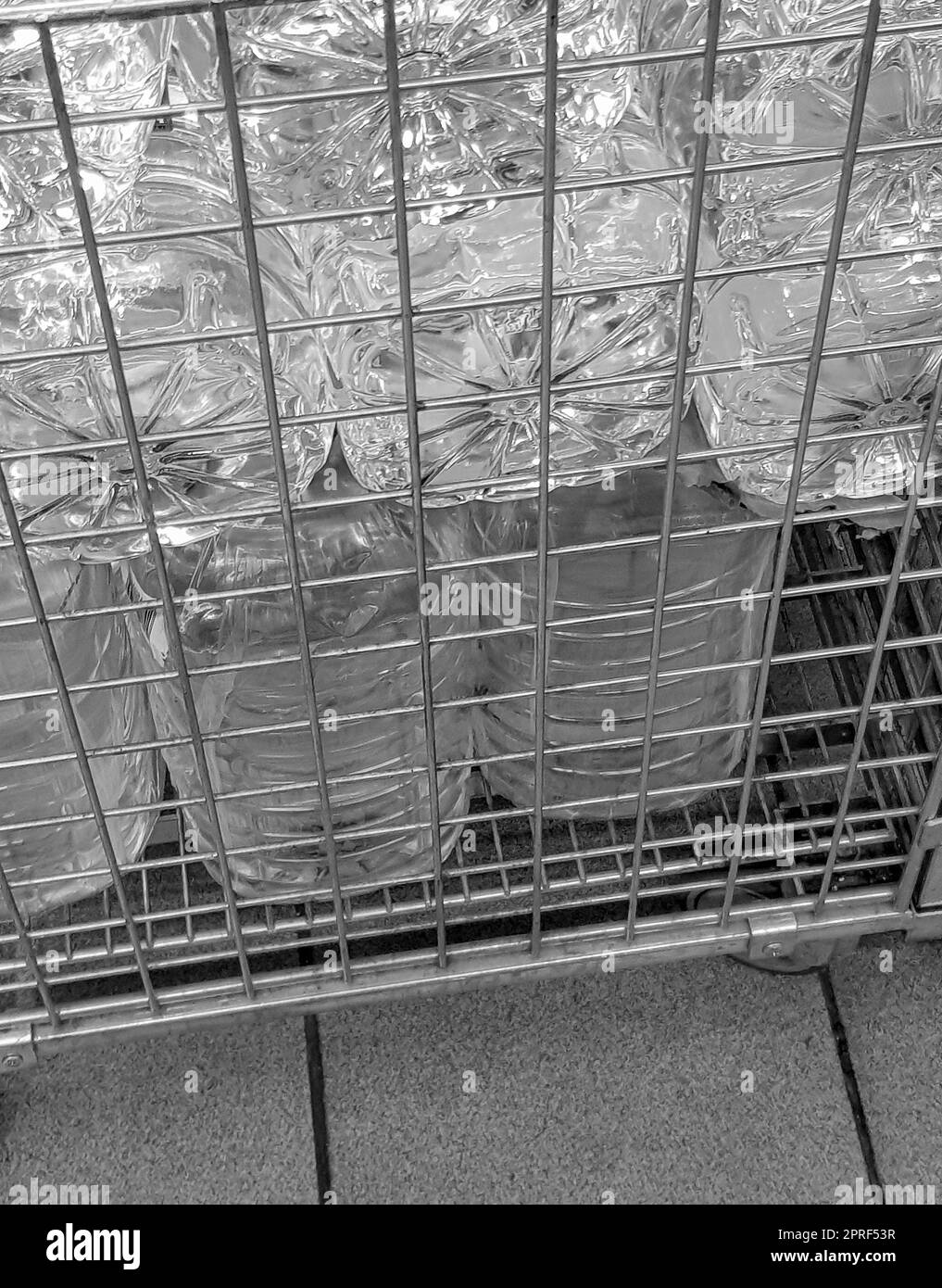 Lagerung und Transport von großen Plastikflaschen für sauberes Trinkwasser in einem Behälter mit Metallrost, Nahaufnahme Stockfoto