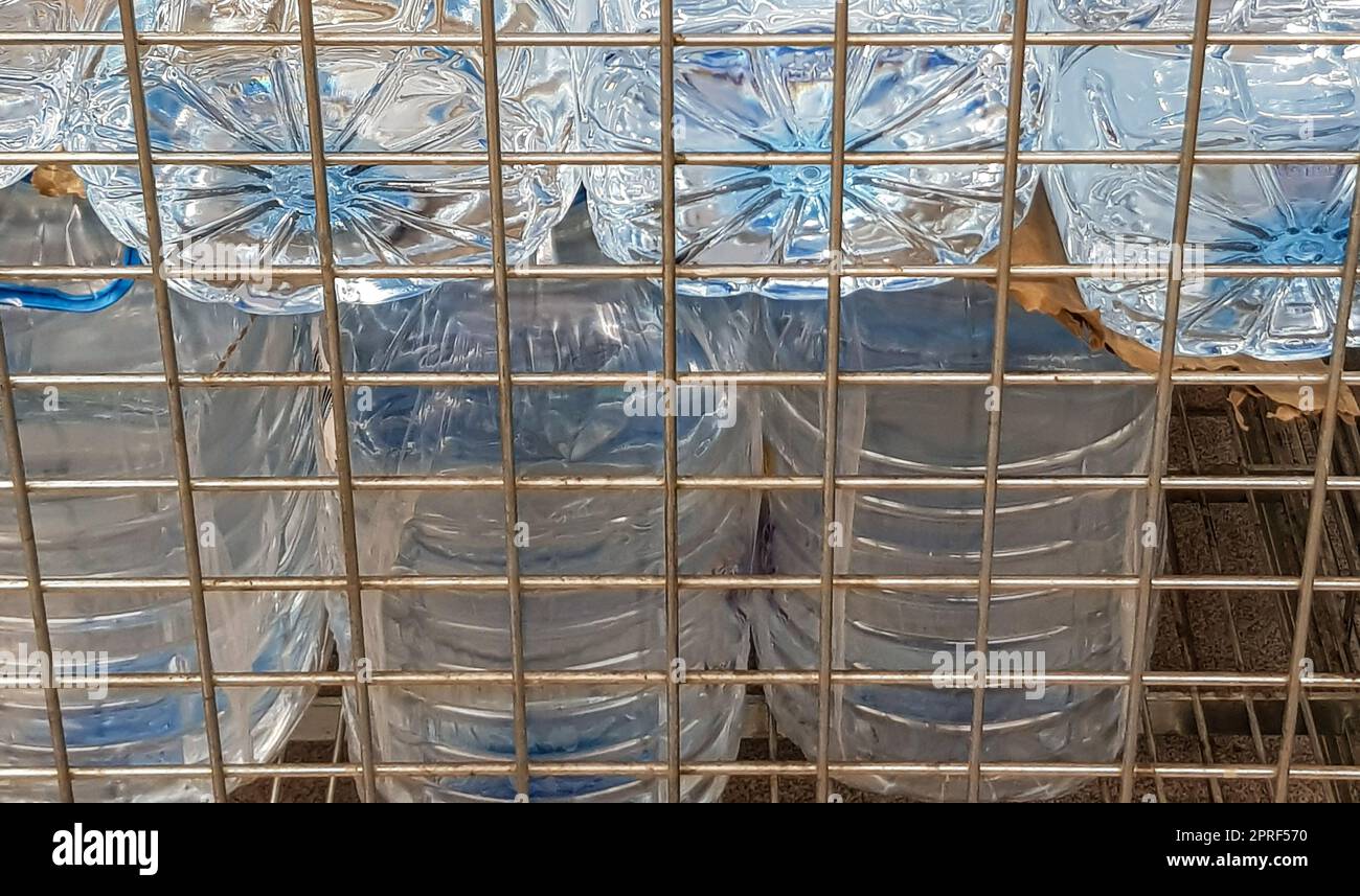 Lagerung und Transport von großen Plastikflaschen für sauberes Trinkwasser in einem Behälter mit Metallrost, Nahaufnahme Stockfoto